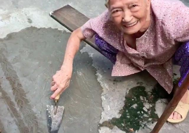 Xôn xao clip cụ bà ngoài 80 tuổi tự trộn xi-măng “vá” đường ở TP.HCM