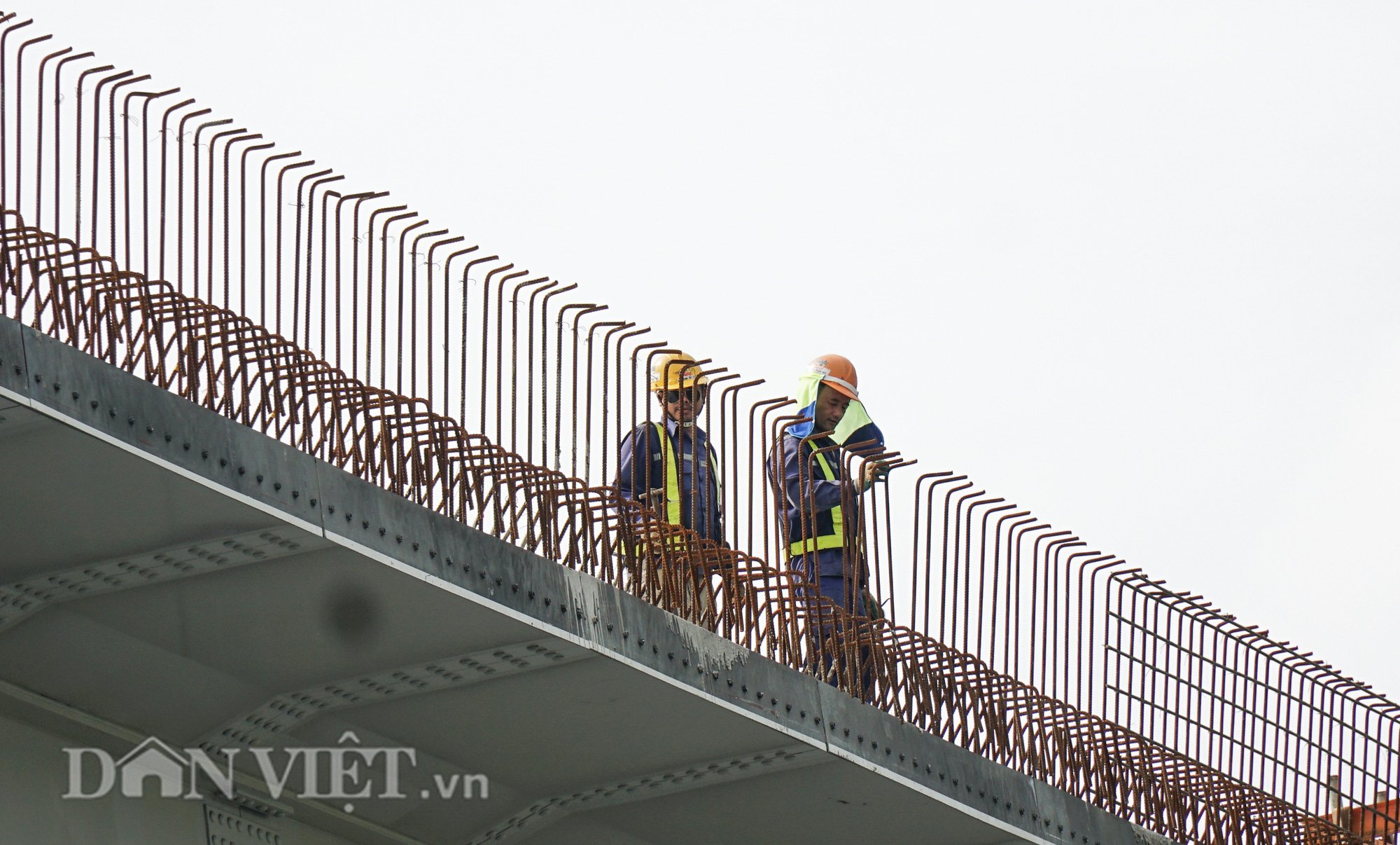 Nhiều đoạn cầu cạn hoàn thành việc lắp dầm đang được thi công phần lan can bê tông. Trên mặt cầu, công nhân chia thành nhóm nhỏ hoàn thiện phần bản mặt với kết cấu thép, bê tông.