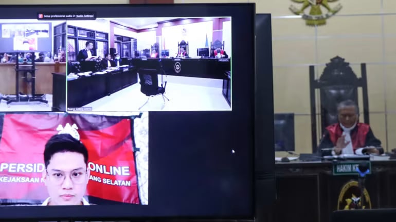 Indra Kesuma, phía dưới bên trái, còn được gọi là Indra Kenz, được cho là đang tham dự phiên điều trần đầu tiên của mình thông qua liên kết video vào ngày 12 tháng 8 tại một tòa án bên ngoài Jakarta. Ảnh của Erwida Maulia.