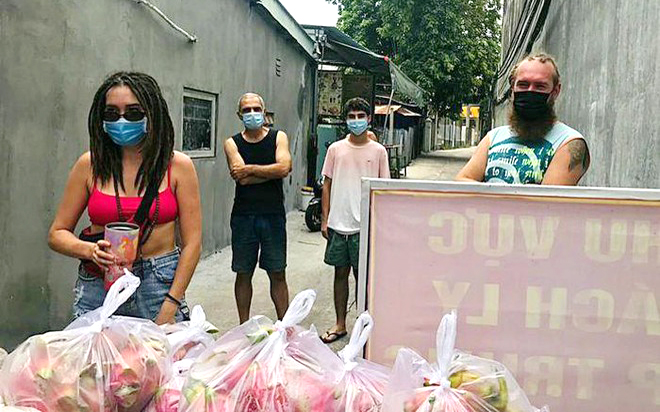 Người nước ngoài ở hẻm 69 nhận quà hỗ trợ từ chính quyền tại chốt kiểm dịch ngay đầu hẻm. Ảnh: Lâm Khoa